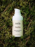 Nellie Peptide Age-Defying Eye Cream 15 ml by Norla, small airless pump bottle lying on green moss