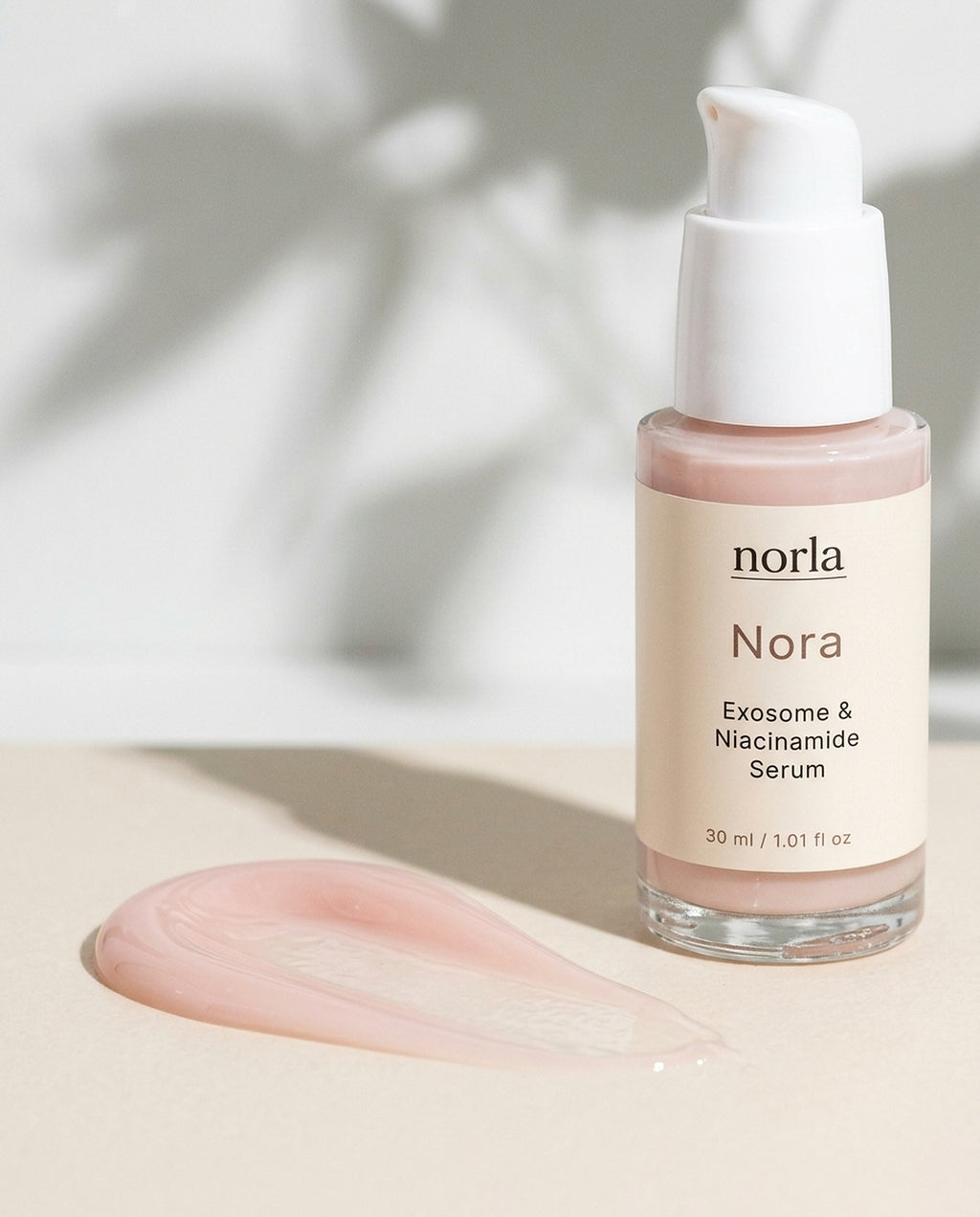 Texture of Nora Exosome & Niacinamide Serum by Norla: a sheer pink serum smear next to the bottle