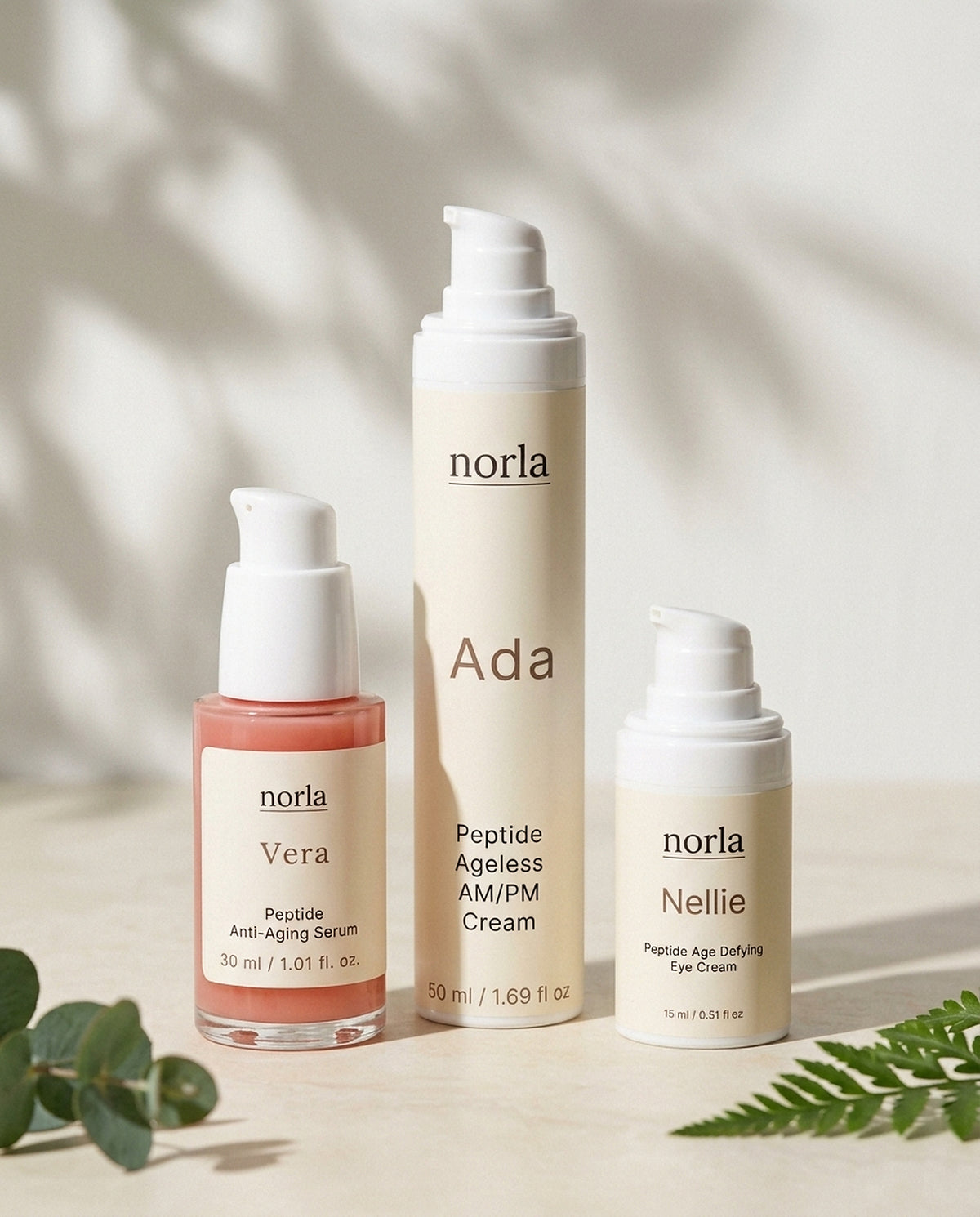 Norla Full Ritual Peptide Trio: Vera peptide serum, Ada AM/PM cream and Nellie eye cream on a marble surface with eucalyptus and fern