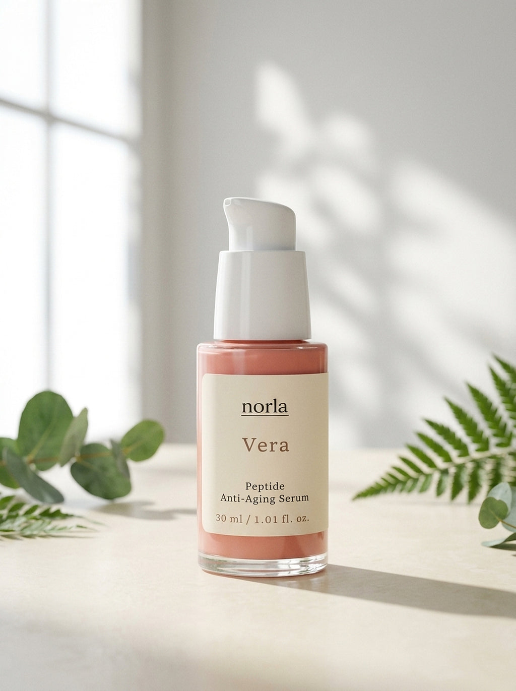 Vera Peptide Anti-Aging Serum 30 ml by Norla, glass pump bottle on a marble surface in soft daylight with fern leaves